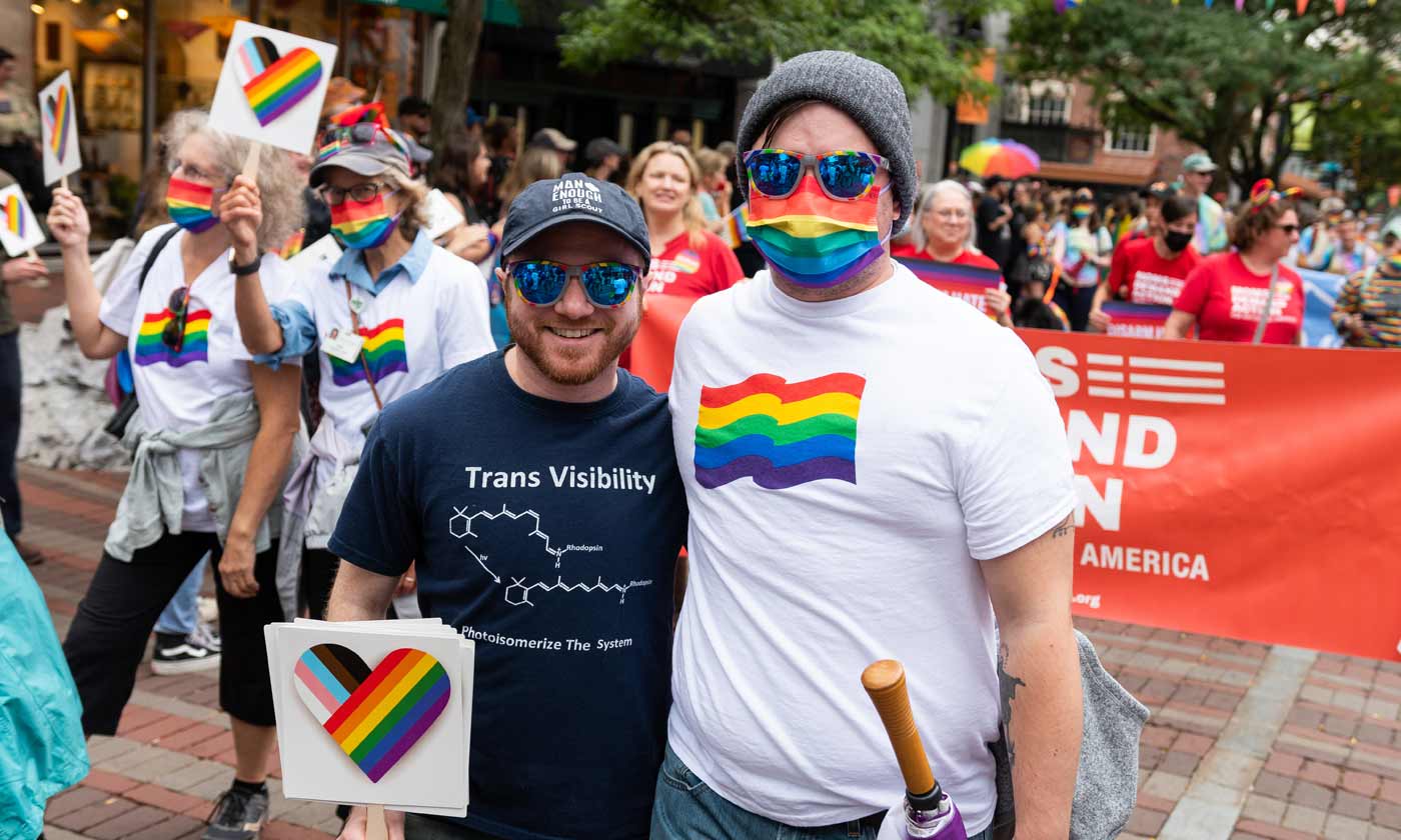 Two smiling individuals at Pride parade smiling at camera