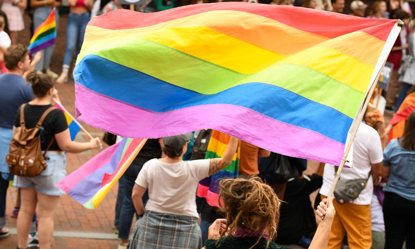 Group of people waving Pride flag at Pride parade