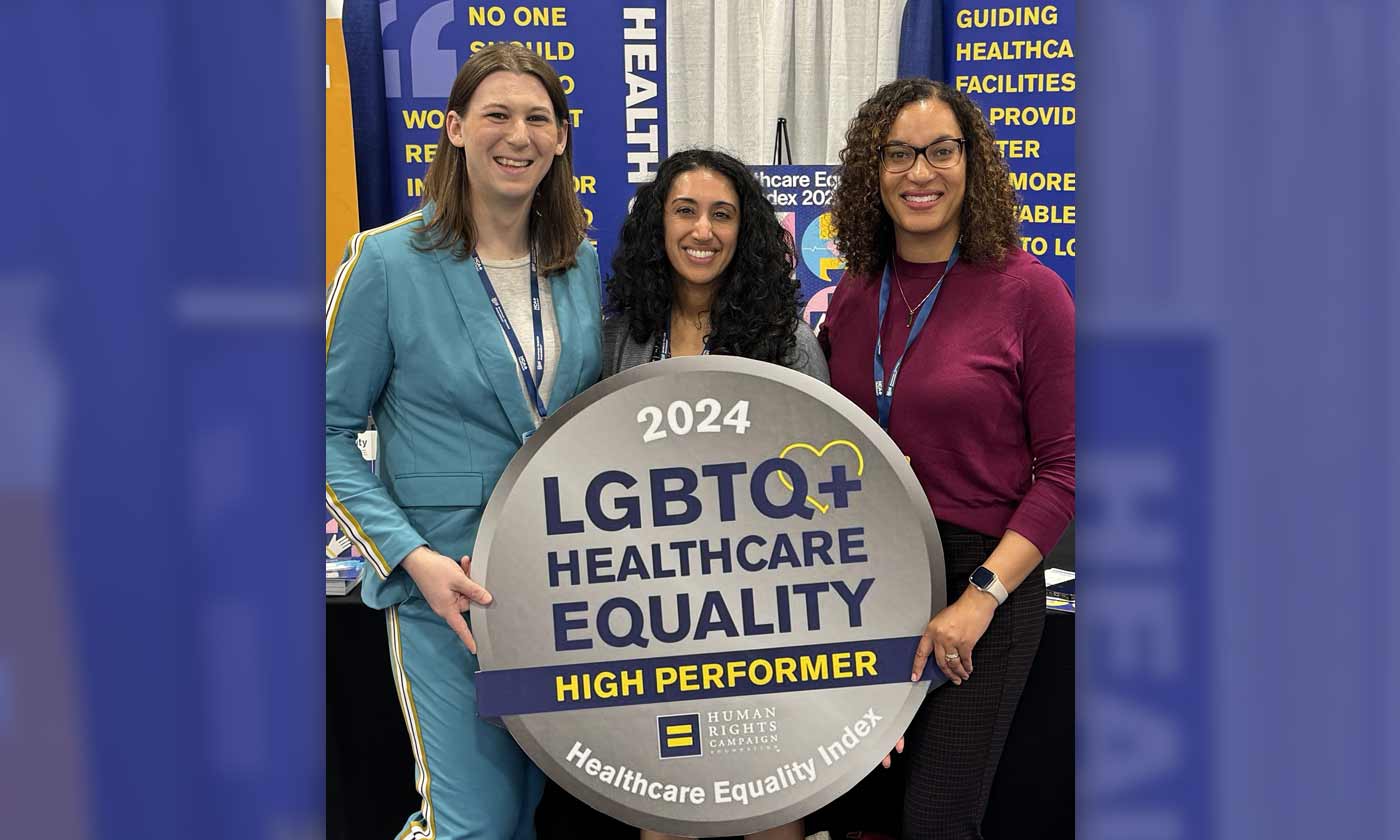 Three individuals holding sign indicating 2024 award for LGBTQ+ Healthcare Equality High Performer